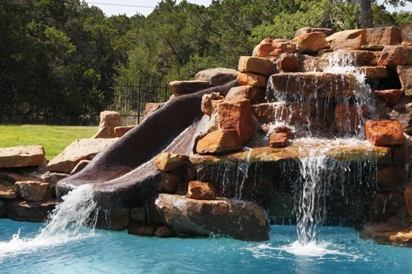 Pool fountain - mid-sized rustic backyard custom-shaped natural pool fountain idea in Austin with decking