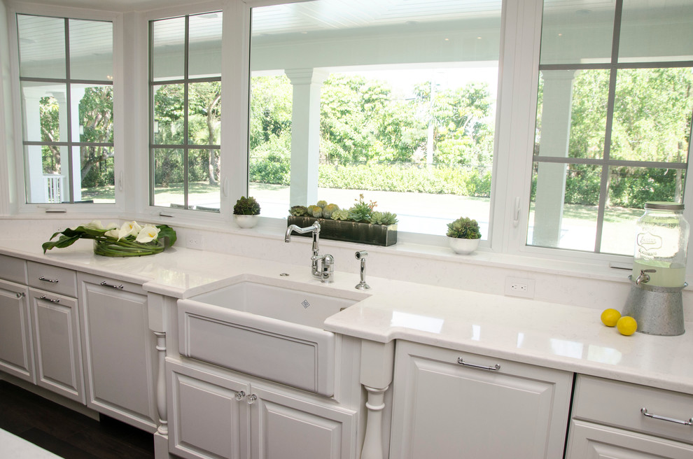 Large transitional u-shaped enclosed kitchen photo in Miami with a farmhouse sink, raised-panel cabinets, white cabinets, quartz countertops, gray backsplash, porcelain backsplash, paneled appliances and an island