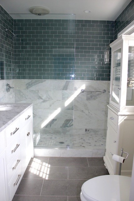 This is an example of a mid-sized transitional master bathroom in DC Metro with flat-panel cabinets, white cabinets, a corner shower, a two-piece toilet, blue tile, subway tile, beige walls, ceramic floors, an undermount sink and marble benchtops.