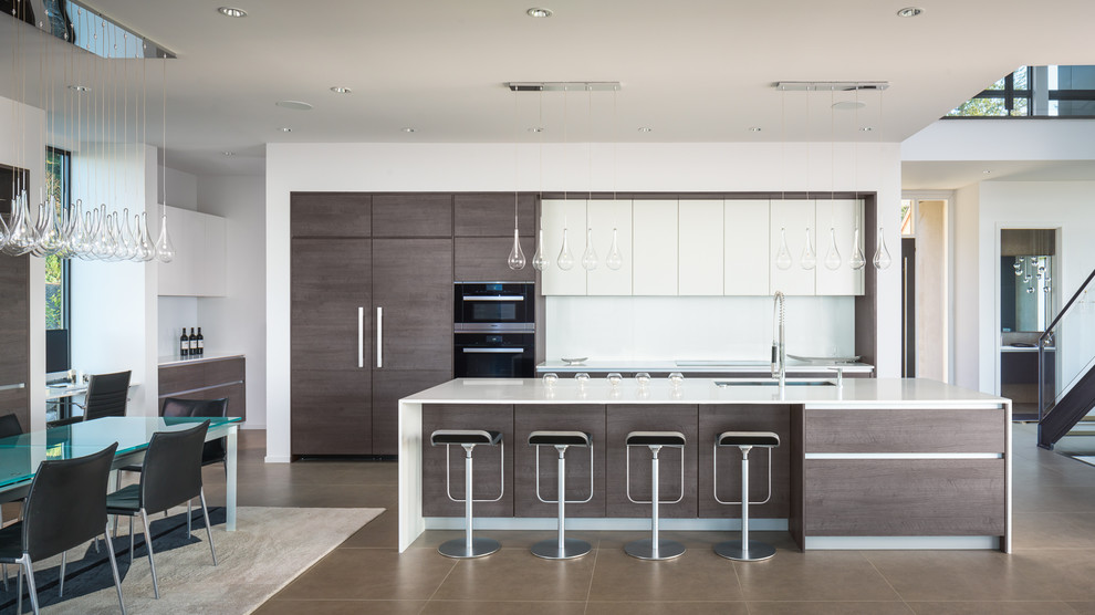 Large contemporary eat-in kitchen in Seattle with an undermount sink, flat-panel cabinets, quartz benchtops, white splashback, panelled appliances, ceramic floors, with island and white cabinets.