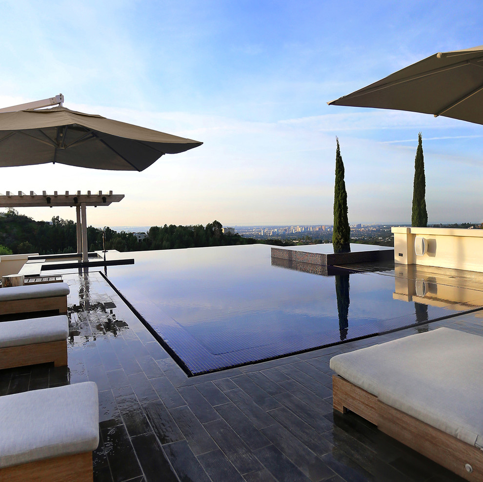 Photo of a large modern backyard custom-shaped infinity pool in Los Angeles with a water feature and tile.
