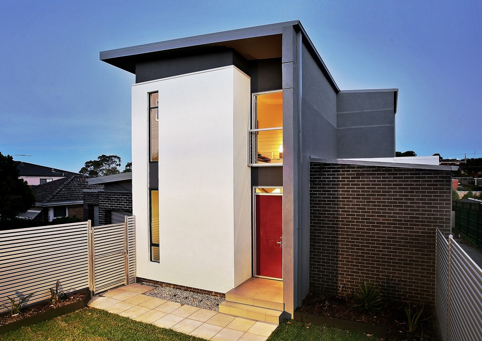 This is an example of a mid-sized modern two-storey brick grey townhouse exterior in Melbourne with a flat roof and a metal roof.