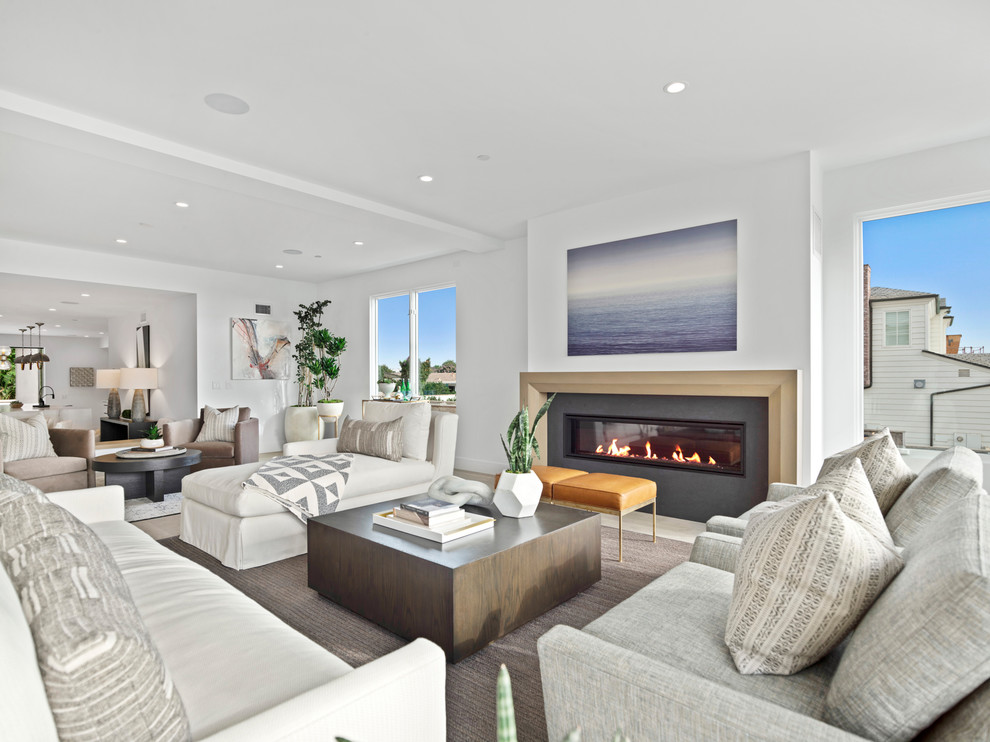 Photo of a large beach style formal open concept living room in Orange County with white walls, limestone floors, a ribbon fireplace, a tile fireplace surround, no tv and white floor.