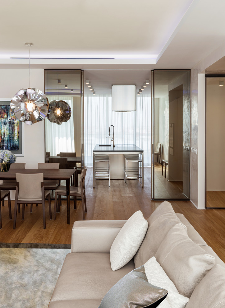 This is an example of a large contemporary open concept living room in Milan with white walls and light hardwood floors.