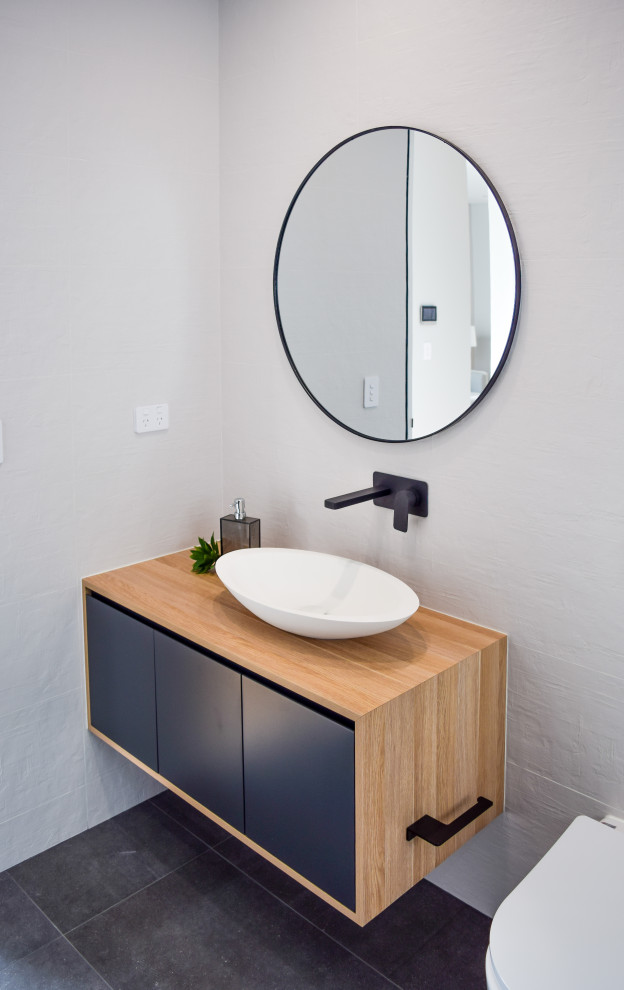 Large contemporary master bathroom in Sydney with black cabinets, a wall-mount toilet, white tile, ceramic tile, porcelain floors, a console sink, laminate benchtops, grey floor, a single vanity and a freestanding vanity.