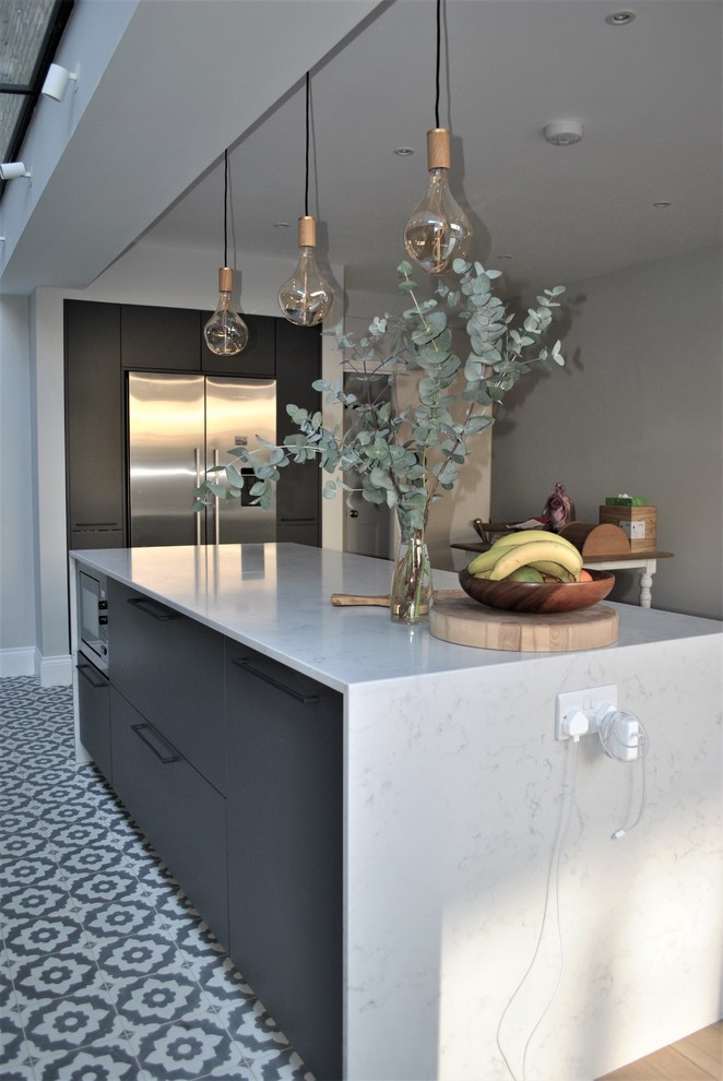 This is an example of a contemporary eat-in kitchen in London with a farmhouse sink, flat-panel cabinets, grey cabinets, quartzite benchtops, white splashback, subway tile splashback, ceramic floors and multi-coloured floor.