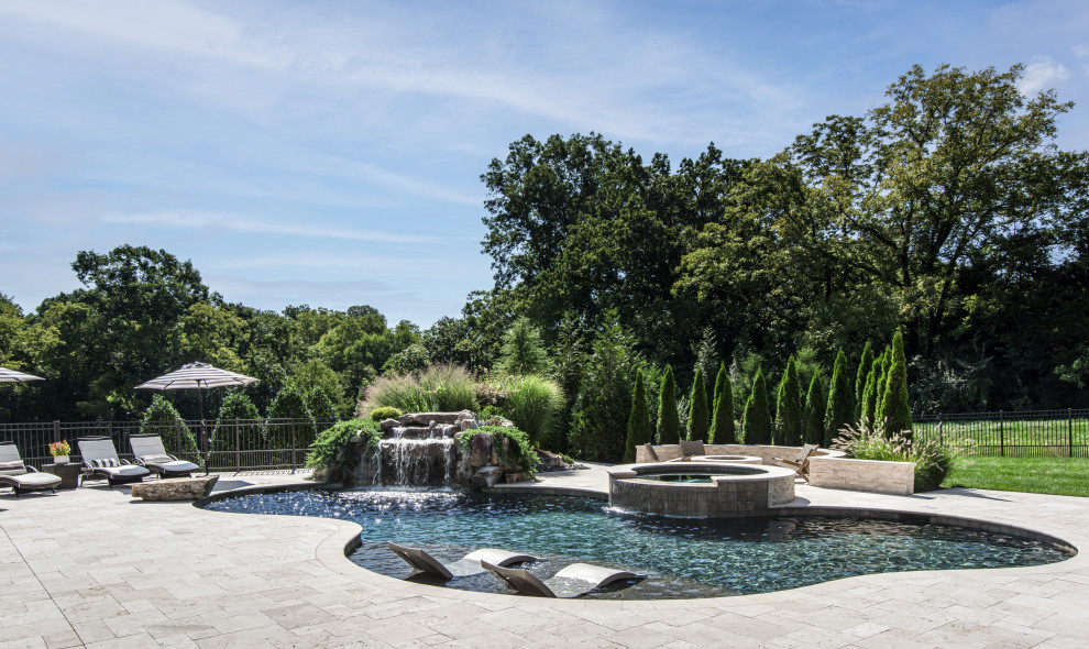 Exemple d'une grande piscine arrière chic en forme de haricot avec un bain bouillonnant et des pavés en pierre naturelle.