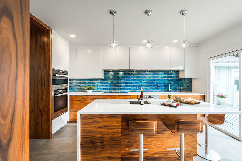 Mid-sized contemporary u-shaped kitchen in Vancouver with a double-bowl sink, flat-panel cabinets, medium wood cabinets, blue splashback, stainless steel appliances and with island.
