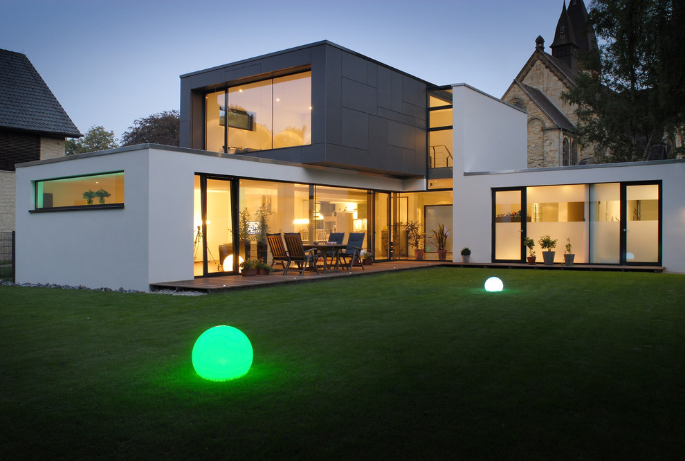 Large contemporary split-level stucco white house exterior in Other with a flat roof.