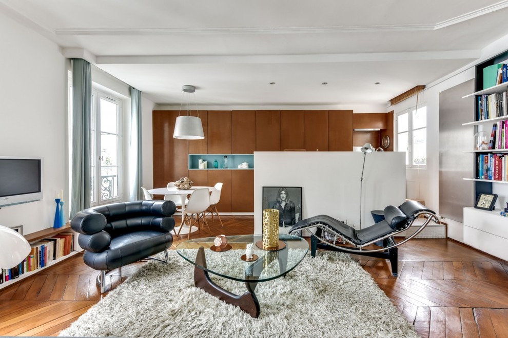 Photo of a contemporary open concept living room in Paris with white walls, medium hardwood floors, a wall-mounted tv and brown floor.