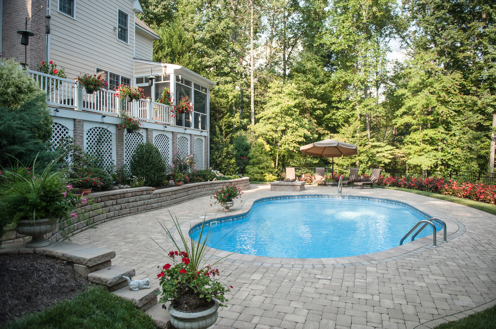 Photo of a large traditional backyard kidney-shaped pool in Richmond with concrete pavers.