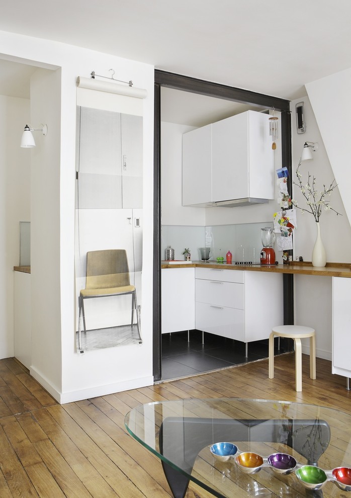 This is an example of a small contemporary u-shaped open plan kitchen in Paris with white cabinets and no island.