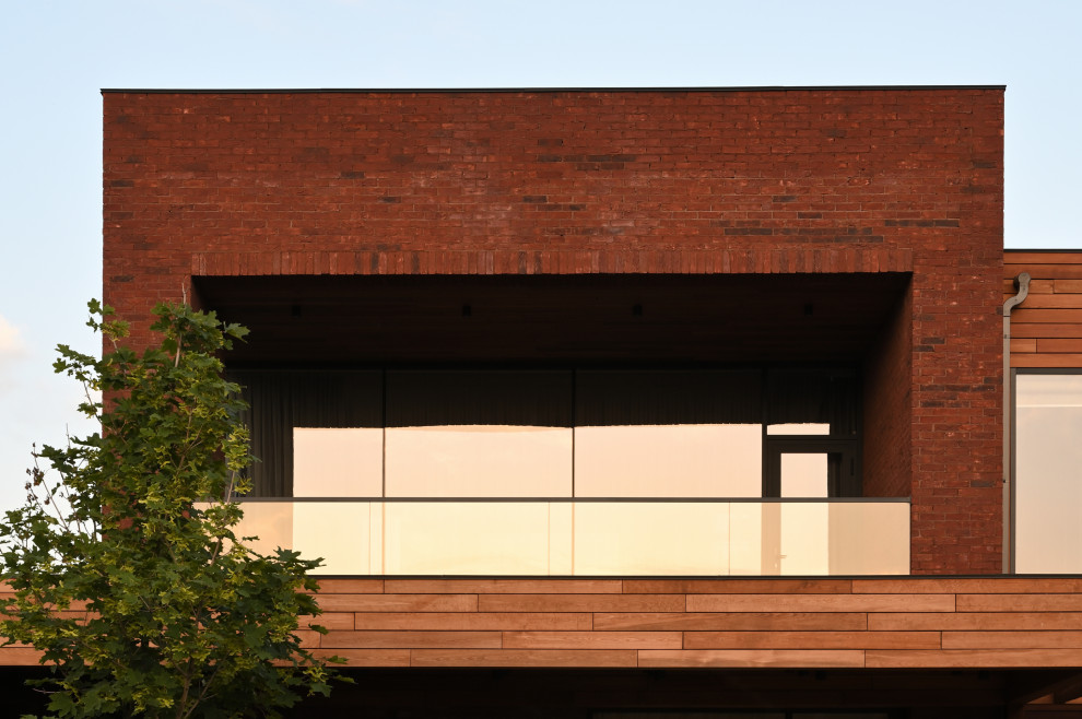 Exemple d'une grande façade de maison marron tendance en brique à un étage avec un toit plat.