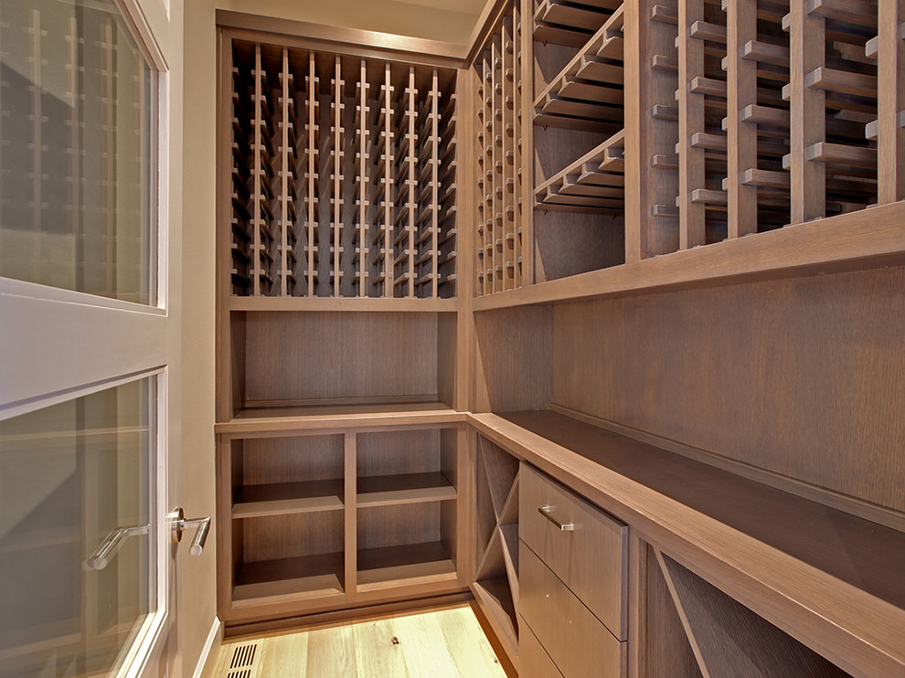 Inspiration for a mid-sized contemporary wine cellar in Portland with light hardwood floors, storage racks and beige floor.