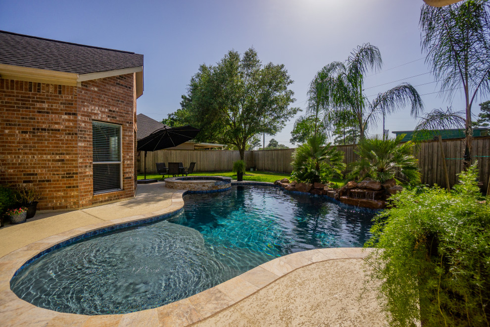 This is an example of a mid-sized tropical backyard custom-shaped pool in Houston with decking.