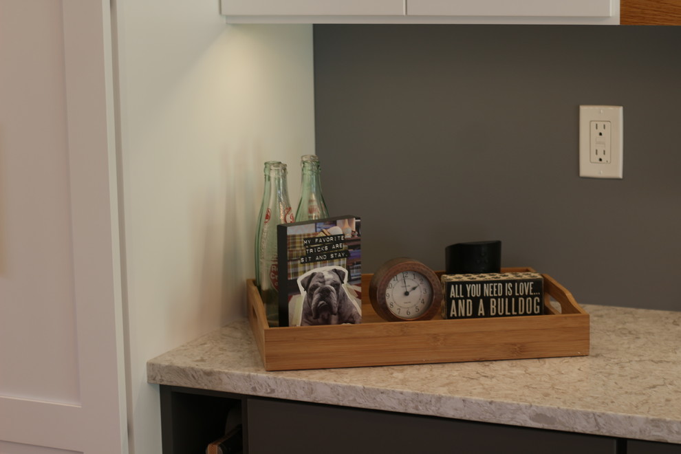 Example of a mid-sized transitional u-shaped medium tone wood floor and brown floor enclosed kitchen design with a farmhouse sink, shaker cabinets, white cabinets, quartz countertops, white backsplash, subway tile backsplash, white appliances, no island and beige countertops