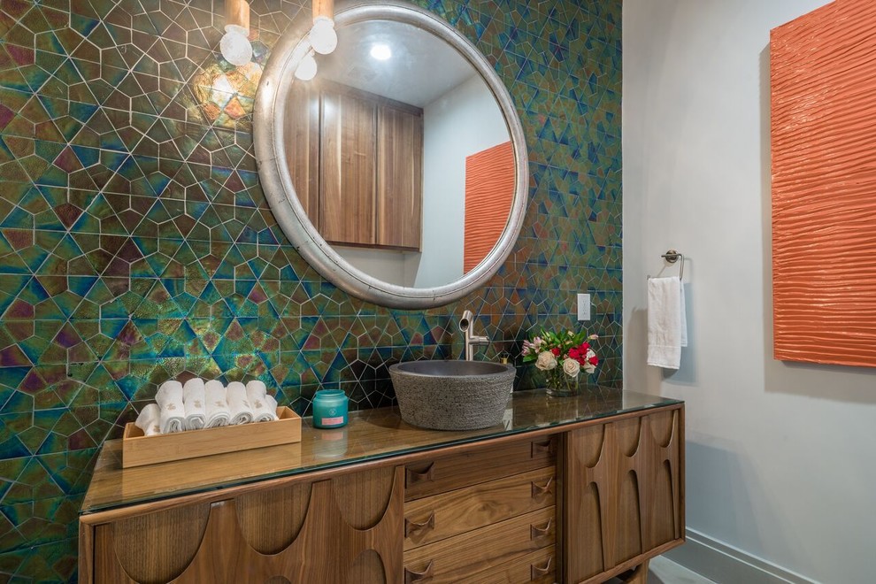 Transitional powder room in Dallas with furniture-like cabinets, medium wood cabinets, multi-coloured tile, white walls, a vessel sink and glass benchtops.