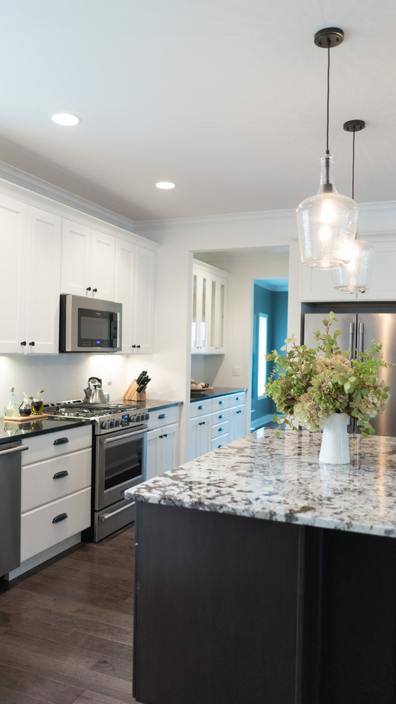 Example of a mid-sized transitional l-shaped dark wood floor open concept kitchen design with an undermount sink, shaker cabinets, white cabinets, granite countertops, gray backsplash, stainless steel appliances and an island