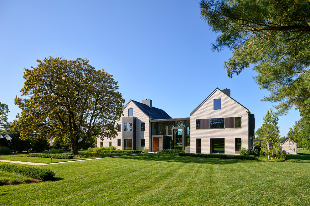 На фото: большой, двухэтажный, разноцветный частный загородный дом в стиле модернизм с комбинированной облицовкой, двускатной крышей, металлической крышей, отделкой дранкой, входной группой и черной крышей с