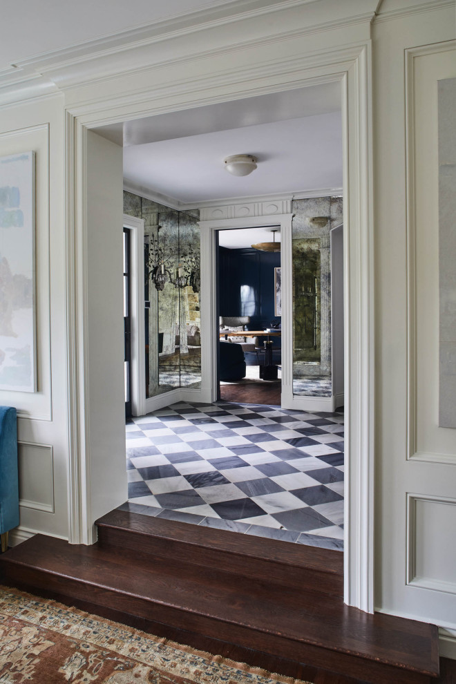 Immagine di un ingresso tradizionale con pareti bianche, pavimento in marmo, pavimento multicolore e pannellatura
