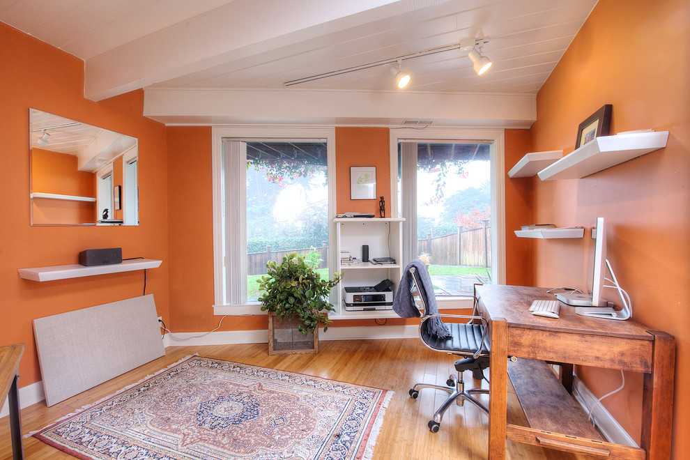 Photo of a small eclectic study room in San Francisco with orange walls, light hardwood floors and a freestanding desk.