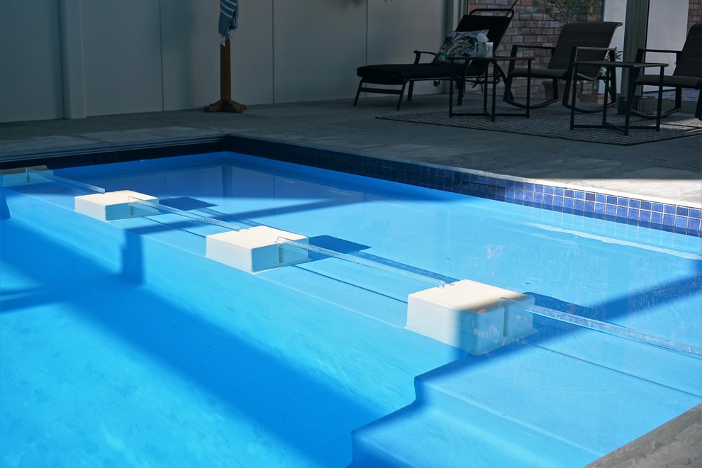 Photo of a mid-sized modern indoor custom-shaped natural pool in Auckland with concrete slab.