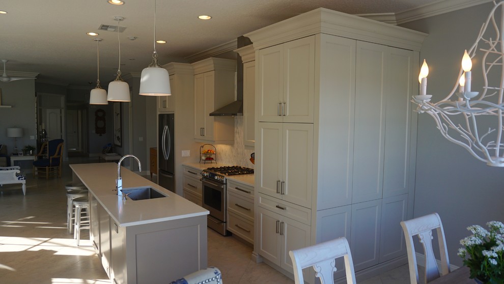 Open concept kitchen - mid-sized transitional l-shaped ceramic tile and beige floor open concept kitchen idea in Miami with an undermount sink, recessed-panel cabinets, beige cabinets, solid surface countertops, beige backsplash, mosaic tile backsplash, stainless steel appliances and an island