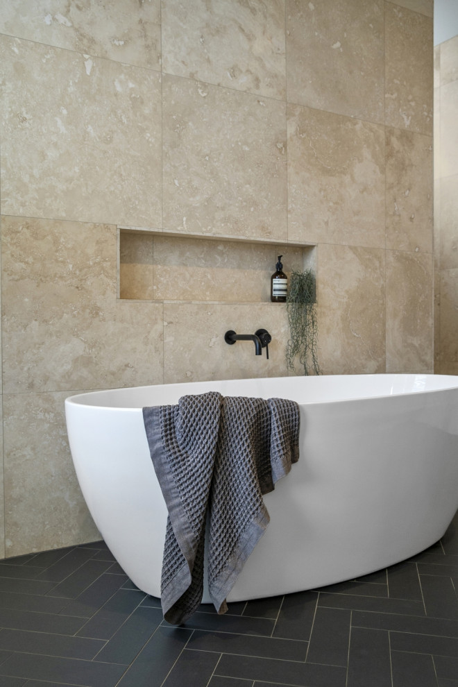 Modern inredning av ett stort en-suite badrum, med släta luckor, bruna skåp, ett fristående badkar, en öppen dusch, beige kakel, kakelplattor, beige väggar, klinkergolv i keramik, svart golv och med dusch som är öppen
