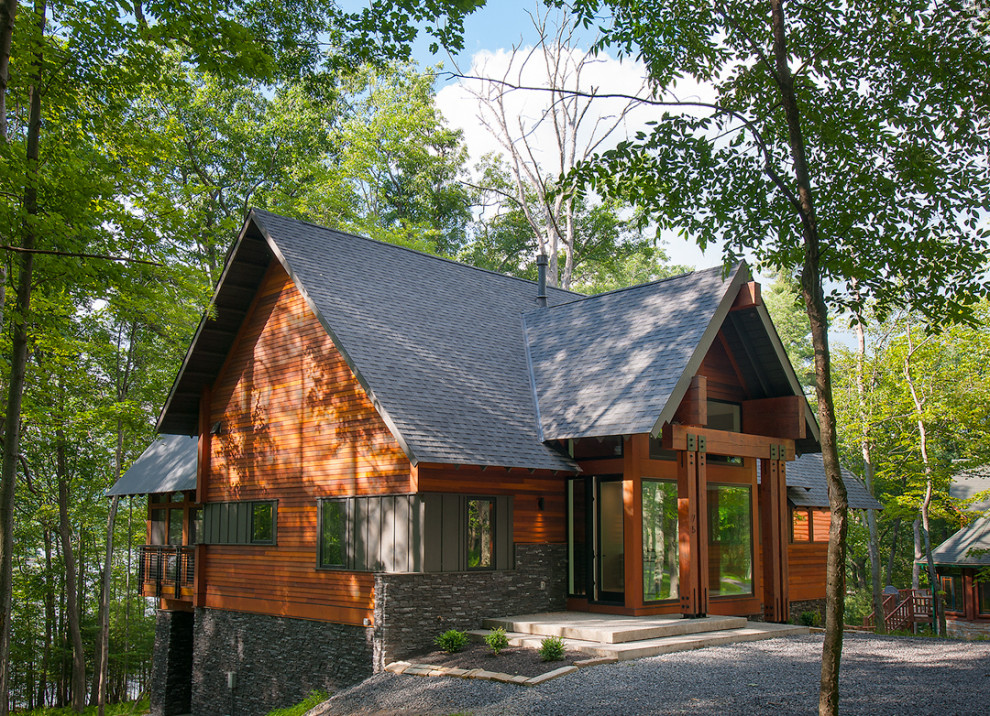 Пример оригинального дизайна: двухэтажный, деревянный, коричневый частный загородный дом среднего размера в стиле неоклассика (современная классика) с двускатной крышей, крышей из гибкой черепицы, черной крышей и отделкой планкеном