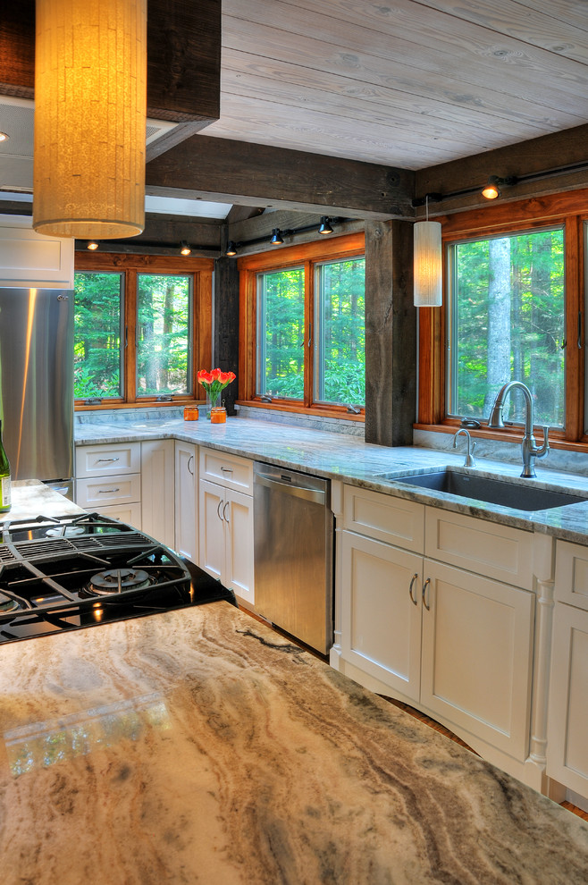 This is an example of a large transitional l-shaped eat-in kitchen in Boston with an undermount sink, shaker cabinets, white cabinets, stainless steel appliances, light hardwood floors, with island, quartzite benchtops and beige floor.