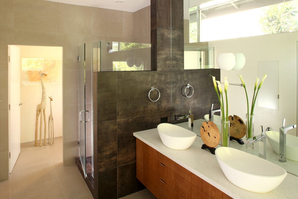 Mid-sized modern master bathroom in Los Angeles with a vessel sink, flat-panel cabinets, medium wood cabinets, a freestanding tub, beige tile, stone tile, beige walls, porcelain floors, engineered quartz benchtops, beige floor and white benchtops.