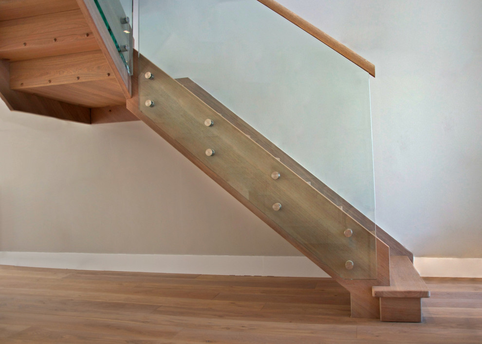 This is an example of a mid-sized country wood l-shaped staircase in Buckinghamshire with wood risers and glass railing.