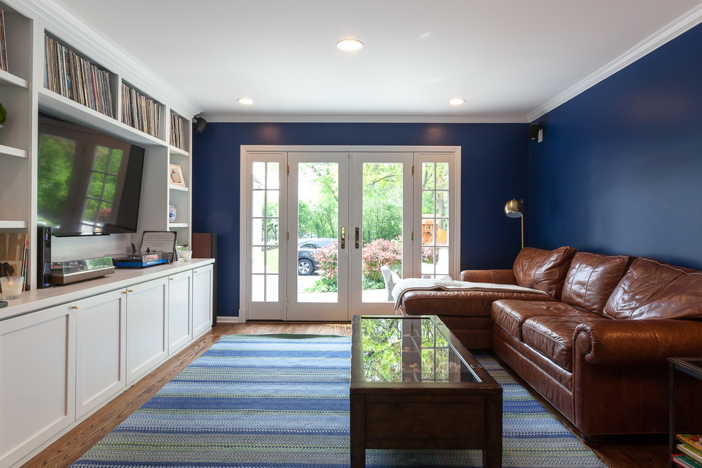 This is an example of a mid-sized transitional open concept family room in Chicago with blue walls, medium hardwood floors, a built-in media wall and brown floor.