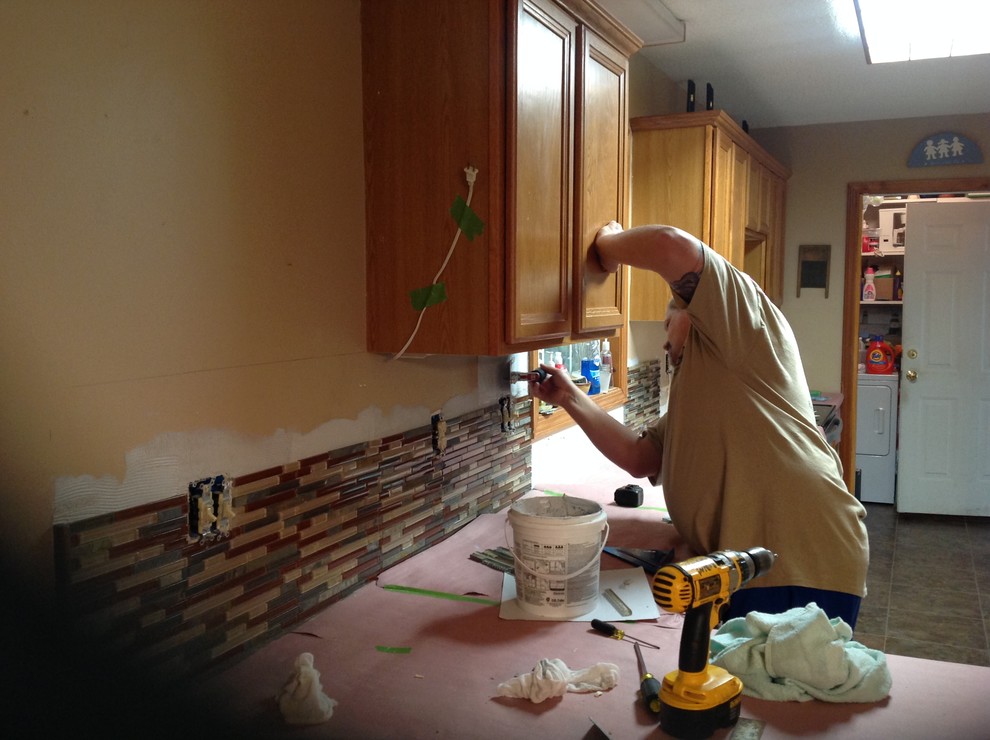 Inspiration for a l-shaped eat-in kitchen remodel with an undermount sink, flat-panel cabinets, brown backsplash, glass tile backsplash, stainless steel appliances and a peninsula