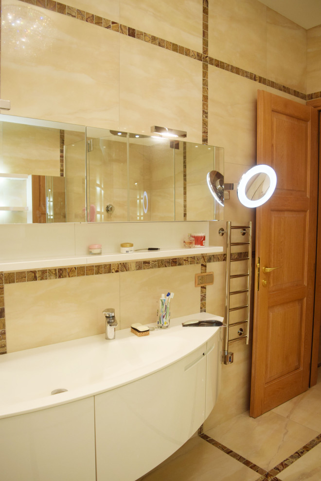 Design ideas for a medium sized eclectic cloakroom in Moscow with glass-front cabinets, white cabinets, a wall mounted toilet, beige tiles, ceramic tiles, beige walls, ceramic flooring, a built-in sink, solid surface worktops, beige floors, white worktops, feature lighting, a freestanding vanity unit, a drop ceiling and wainscoting.