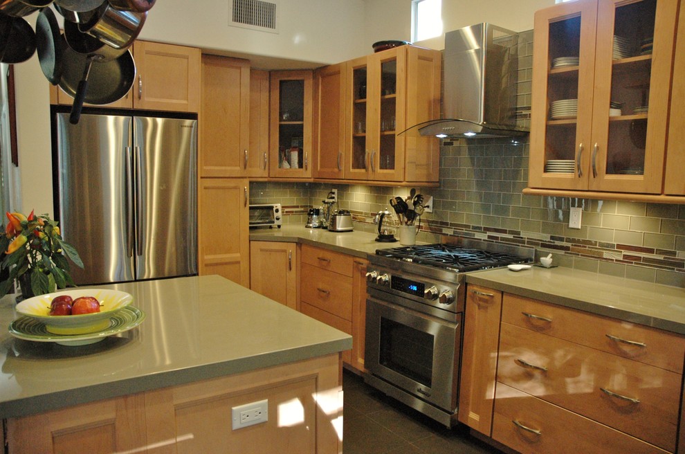 Example of a mid-sized transitional u-shaped slate floor eat-in kitchen design in Orange County with glass-front cabinets, light wood cabinets, quartz countertops, green backsplash, glass tile backsplash, stainless steel appliances and an island