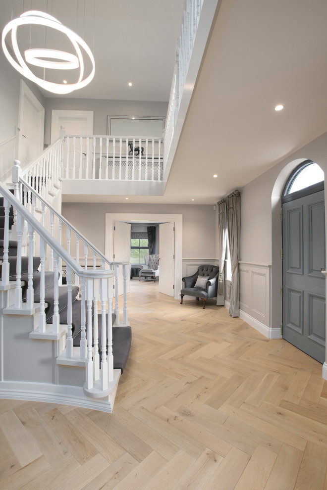 This is an example of a large contemporary entry hall in Dublin with grey walls, light hardwood floors, a single front door, a gray front door and grey floor.