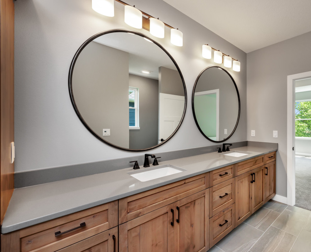 Example of a transitional master gray tile and ceramic tile ceramic tile, gray floor and double-sink doorless shower design in Cedar Rapids with shaker cabinets, medium tone wood cabinets, gray walls, an undermount sink, quartz countertops, a hinged shower door, gray countertops and a built-in vanity