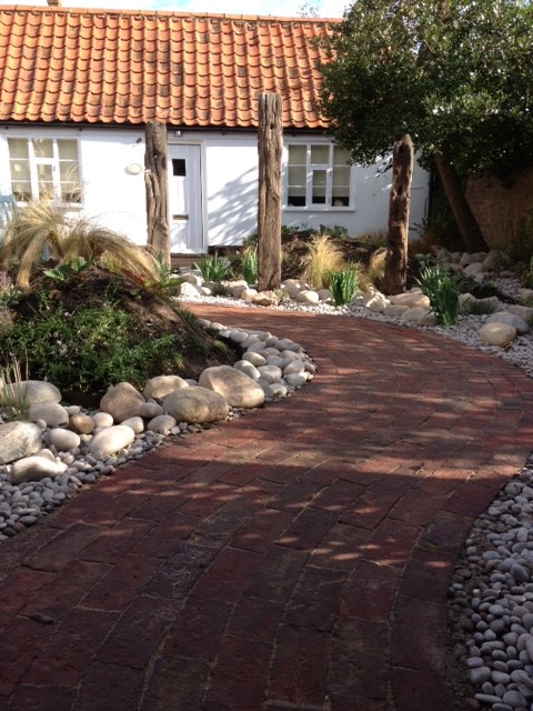 Small shabby-chic style back formal garden in Hertfordshire with a garden path and brick paving.