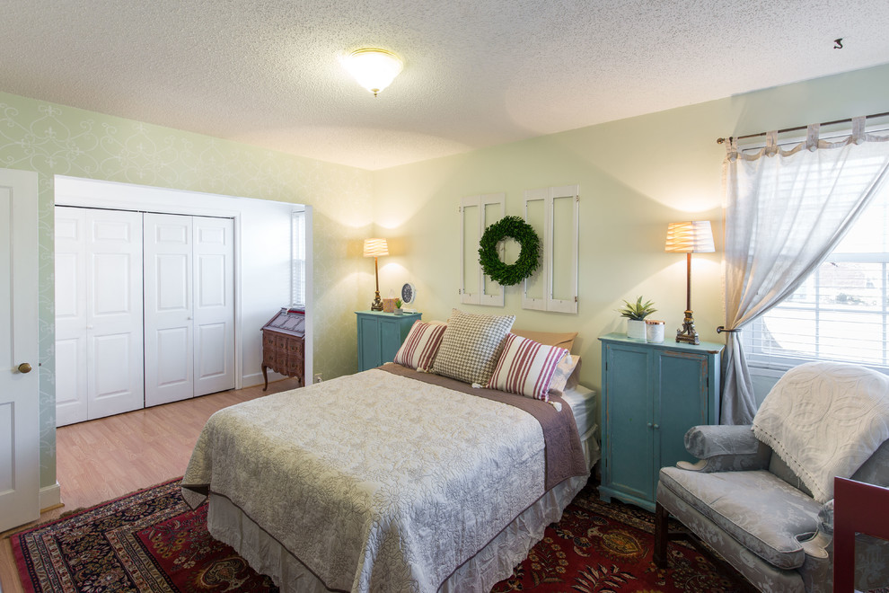 Large traditional master bedroom in Other with green walls, light hardwood floors, no fireplace and beige floor.