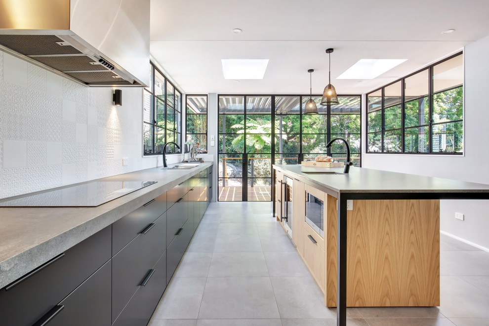 Eat-in kitchen - large modern l-shaped cement tile floor and gray floor eat-in kitchen idea in Sydney with a double-bowl sink, flat-panel cabinets, gray cabinets, quartz countertops, white backsplash, ceramic backsplash, black appliances, an island and gray countertops