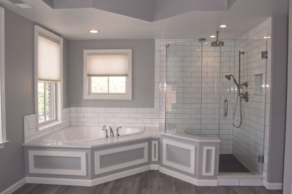 This is an example of a large modern master bathroom in DC Metro with white cabinets, a corner tub, a corner shower, white tile, grey walls, linoleum floors, grey floor and a hinged shower door.