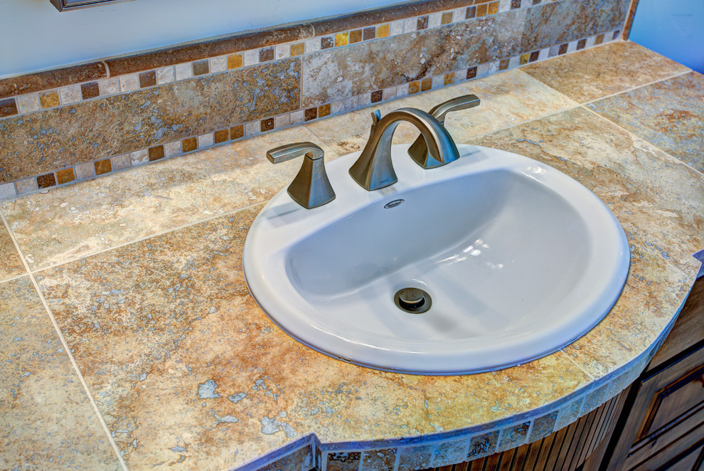 Large mountain style 3/4 multicolored tile bathroom photo with a drop-in sink, raised-panel cabinets, medium tone wood cabinets and a one-piece toilet