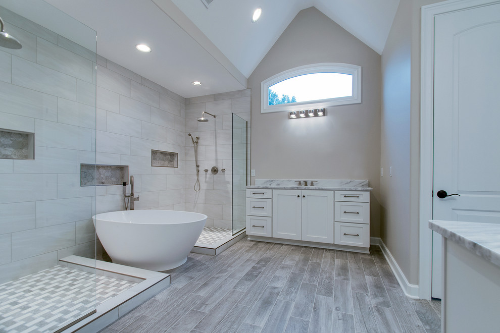 Large transitional master bathroom in Nashville with shaker cabinets, white cabinets, a freestanding tub, an open shower, a one-piece toilet, multi-coloured tile, ceramic tile, grey walls, medium hardwood floors, an undermount sink, quartzite benchtops, brown floor, an open shower and white benchtops.
