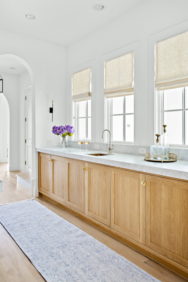 Inspiration för stora klassiska vitt kök, med en undermonterad diskho, skåp i shakerstil, vita skåp, marmorbänkskiva, vitt stänkskydd, stänkskydd i marmor, integrerade vitvaror, ljust trägolv, en köksö och brunt golv
