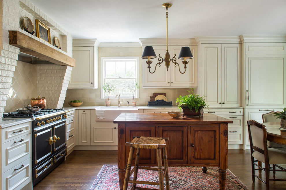 Inspiration for a mid-sized traditional l-shaped eat-in kitchen in Atlanta with a farmhouse sink, raised-panel cabinets, beige splashback, ceramic splashback, black appliances, with island, beige cabinets and dark hardwood floors.