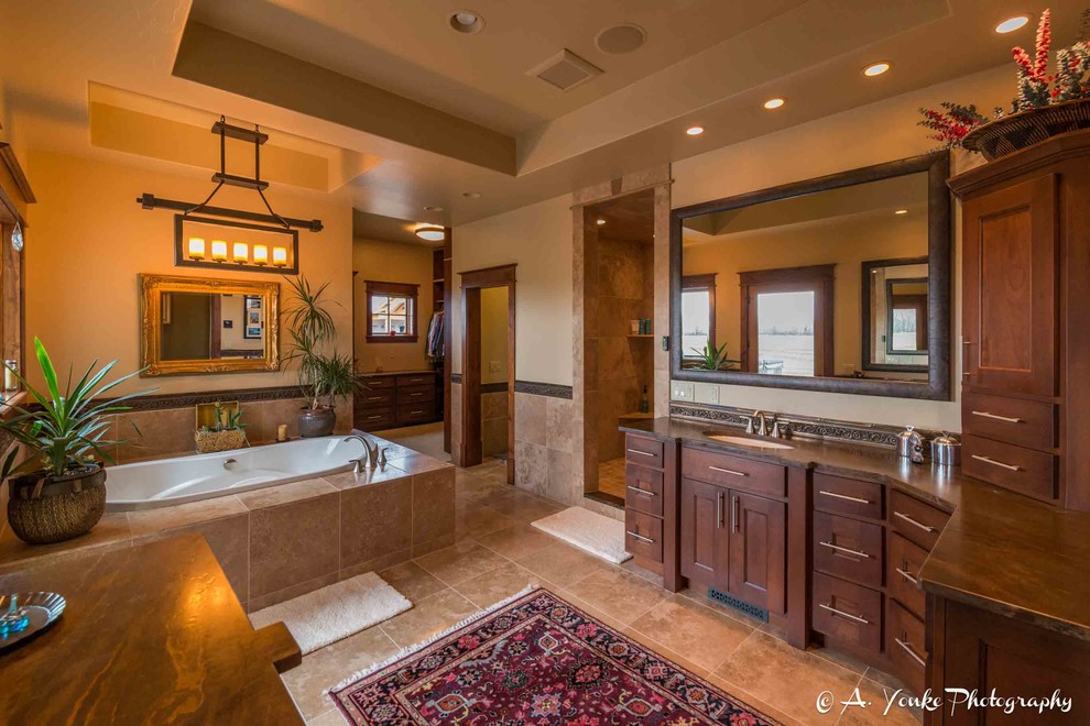 This is an example of a large country master bathroom in Other with shaker cabinets, dark wood cabinets, a drop-in tub, a corner shower, beige tile, brown tile, ceramic tile, beige walls, travertine floors, an undermount sink and soapstone benchtops.