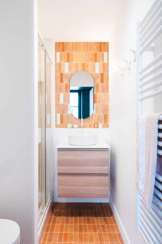 Inredning av ett nordiskt litet vit vitt badrum med dusch, med skåp i ljust trä, en vägghängd toalettstol, orange kakel, keramikplattor, vita väggar, klinkergolv i keramik, ett konsol handfat och orange golv