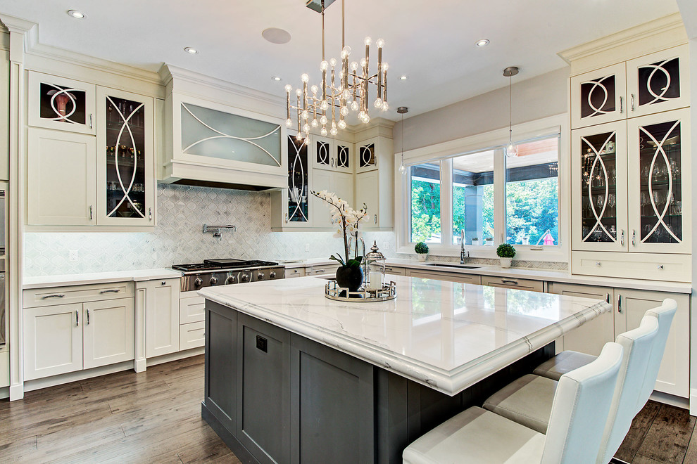Photo of a transitional l-shaped kitchen in Toronto with an undermount sink, glass-front cabinets, beige cabinets, grey splashback, stainless steel appliances, dark hardwood floors, with island, brown floor and white benchtop.