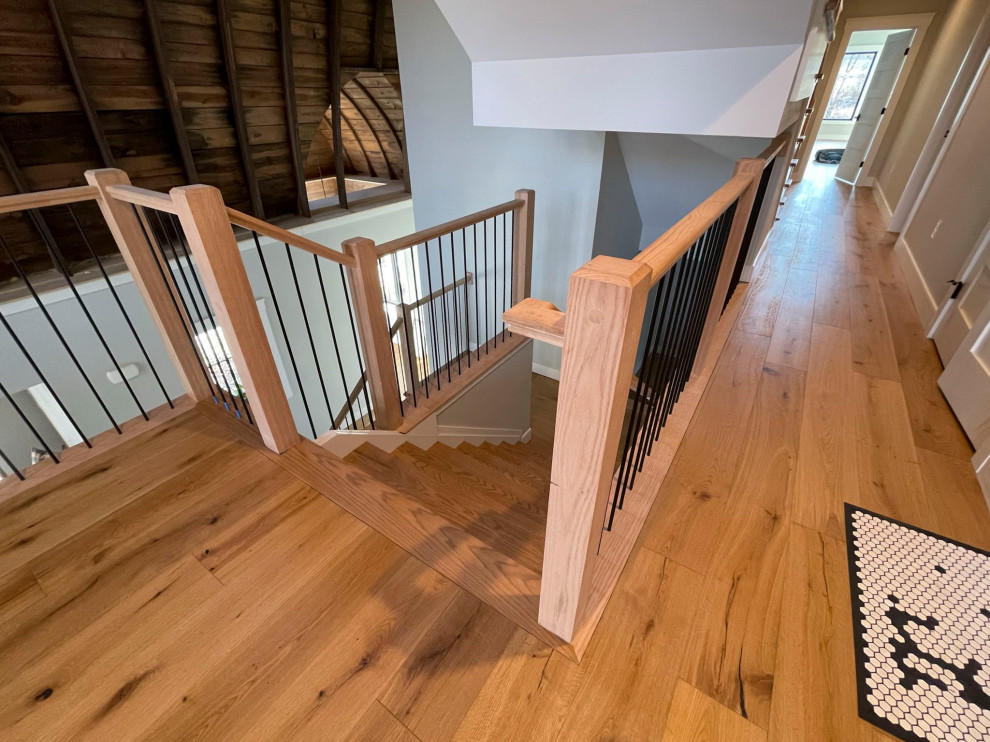 Пример оригинального дизайна: огромная прямая деревянная лестница в стиле неоклассика (современная классика) с деревянными ступенями и перилами из смешанных материалов